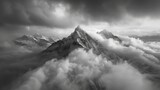 A black and white photograph of a solitary mountain peak surrounded by a sea of dark clouds with hints of fire peeking through. The aerial perspective highlights the isolation