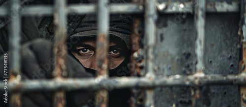 Man in a black hoodie peeking from a metal door