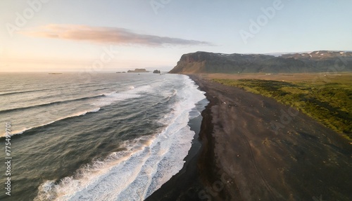 white waves on a black sand beach in a volcanic island in iceland from a drone view