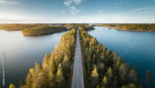 aerial view of road in green woods and blue lakes water in finland