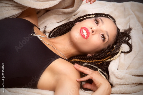 Beautiful young Latina woman reclining into a tan blanket.