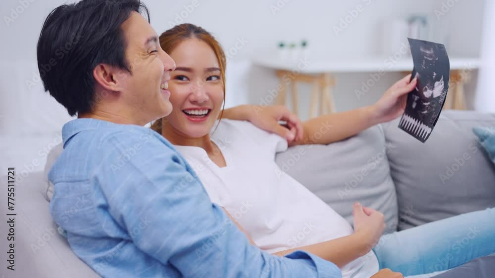 Asian young couple watching ultrasound pregnancy test photo in bedroom. Asian young couple watching ultrasound pregnancy test photo in bedroom.