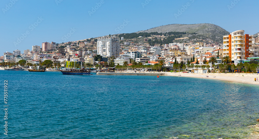 Scenic view of modern cityscape of Sarande on shore of open blue bay of Ionian Sea on sunny spring day, Albania..