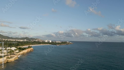 Cupecoy Saint Martin Flying toward Mullet Bay with small plane descending to land on horizon. Aerial drone push-in shot photo