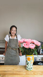 Happy woman in apron at room with flower.