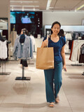 Happy woman doing clothes shopping and holding the product paper bag.