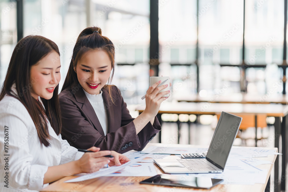 Two engaged businesswomen analyzing reports and sharing insights, with digital devices and financial documents at modern office. Two engaged businesswomen analyzing reports and sharing insights, with digital devices and financial documents at modern office.