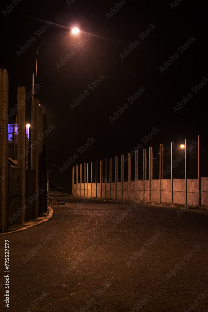 Carretera vacía de noche iluminado con la luz amarilla del poste eléctrico Carretera vacía de noche iluminado con la luz amarilla del poste eléctrico