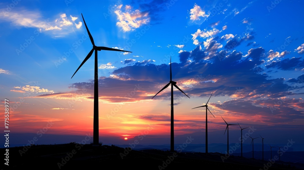 The silhouettes of multiple windmills stand against a colorful sunset sky. Background.