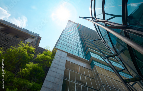 Low angle view of modern glass buildings and green with bright sky © jamesteohart