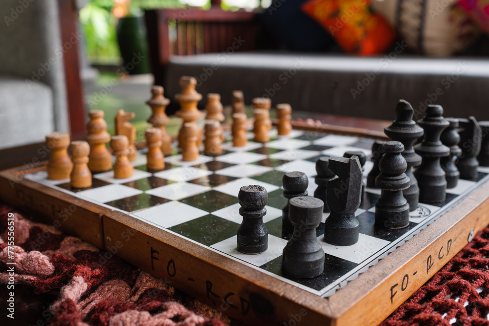 Chess pieces on the board, in a beautiful and cozy hotel interior, with decorative items and greenery in the background. Chess pieces on the board, in a beautiful and cozy hotel interior, with decorative items and greenery in the background.