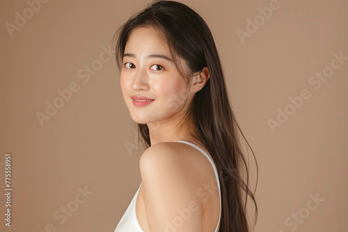 Asian woman with long straight hair looking over her shoulder and smiling at the camera