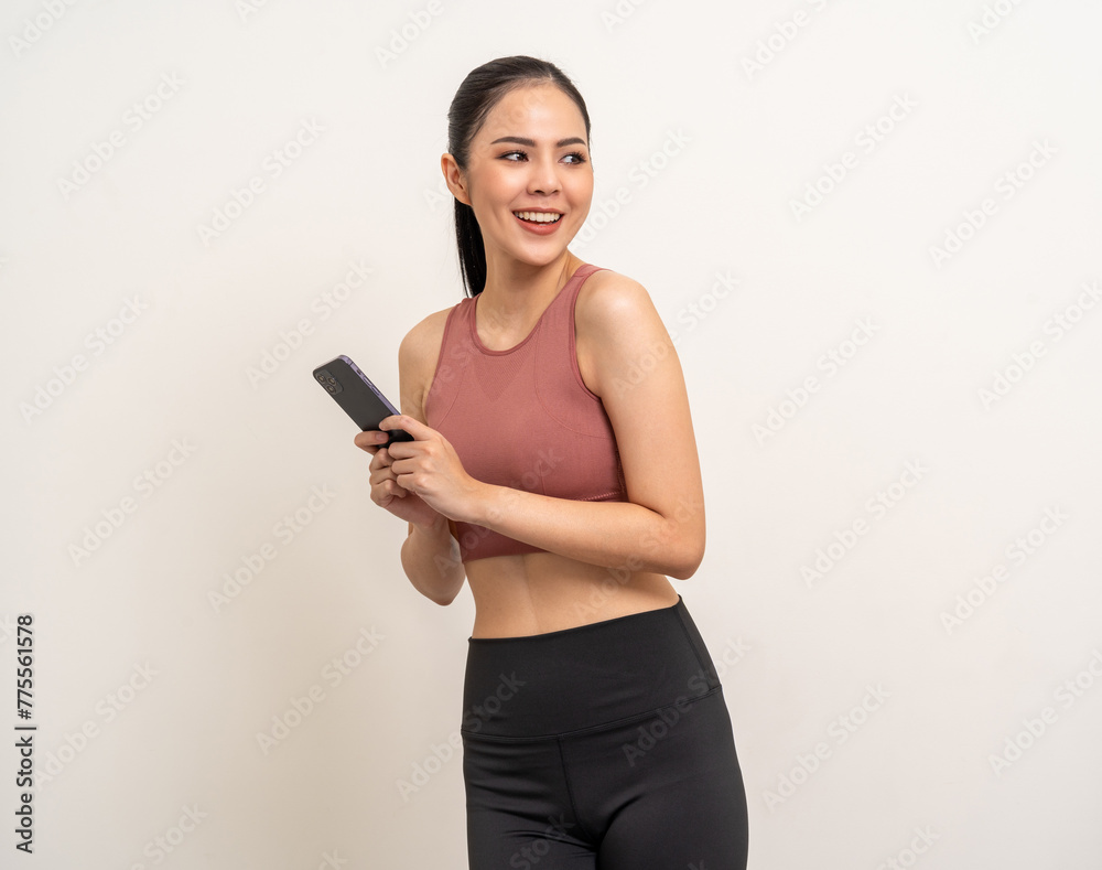 Young beautiful asian woman with sportswear using smartphone on isolated white background. Attractive Portrait latin sporty woman standing pose holding cell phone exercise workout in studio.