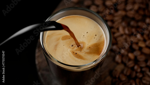 Pouring black coffee espresso with foam in glass