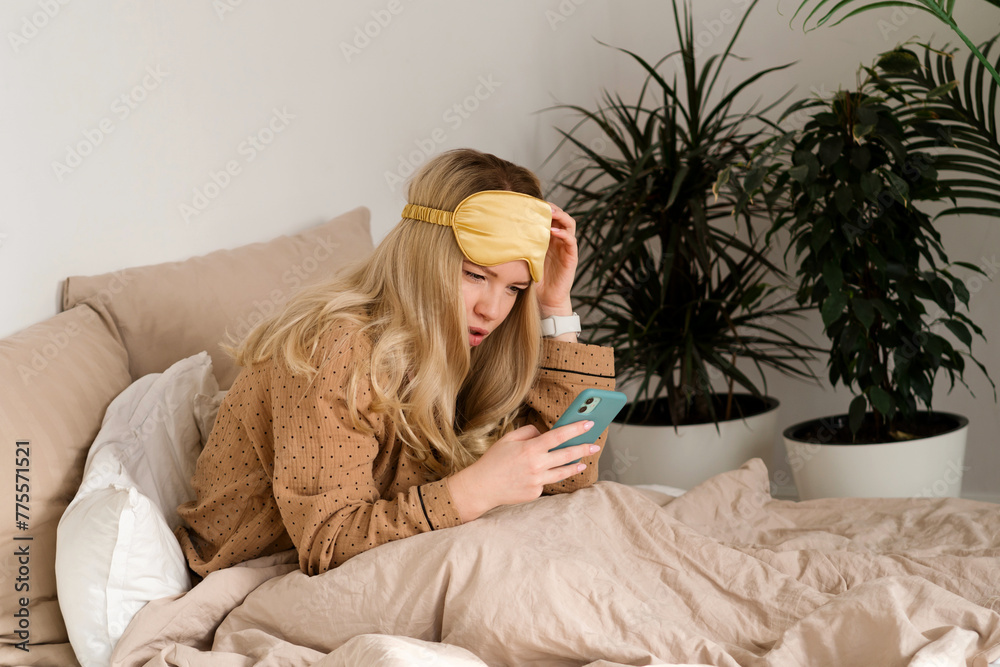 Woman in bed checking phone, concerned look. Woman in bed checking phone, concerned look.