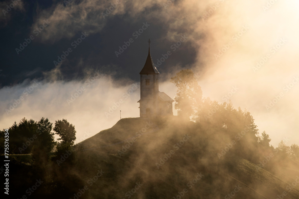 Obraz premium Jamnik, Slovenia - Magical foggy golden summer sunrise at Jamnik St.Primoz church.