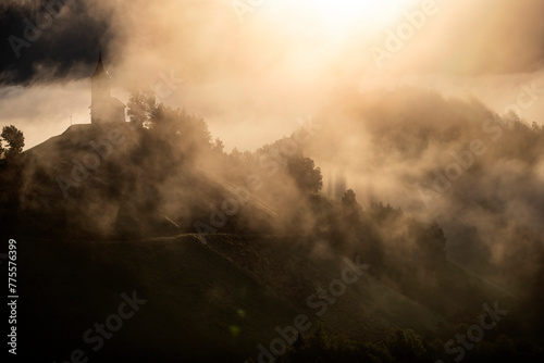 Jamnik, Slovenia - Magical foggy golden summer sunrise at Jamnik St.Primoz church. photo