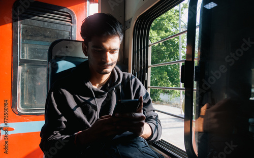 Portrait of a young Indian man travelling in Train. Passenger travelling in local train or unreserved coach.  photo