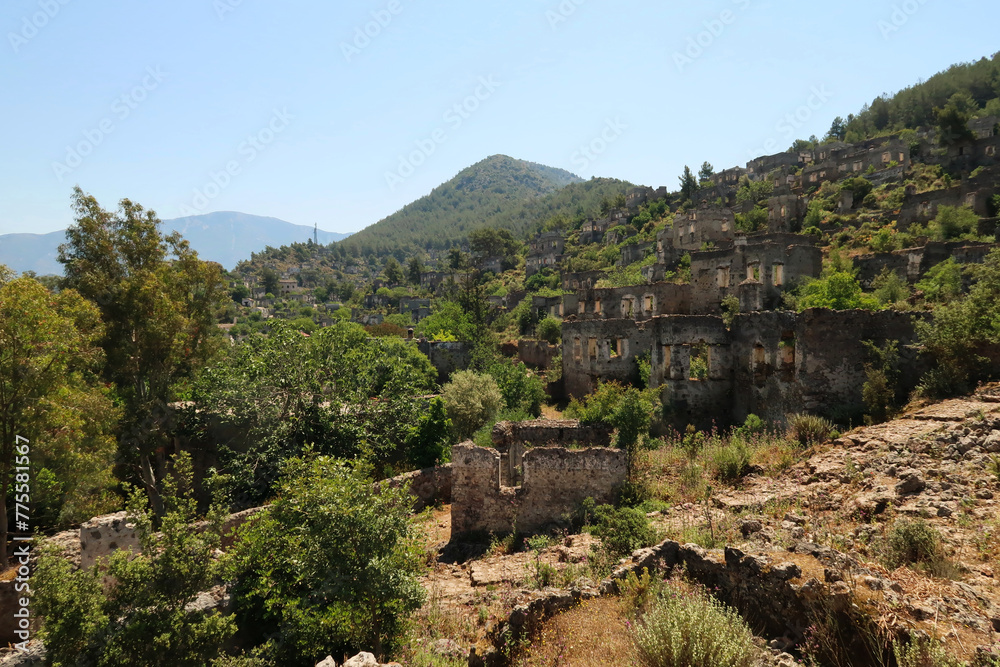 Cobble stone path leading up the hill with the ruins of the abandoned houses of Kayaköy in the background, near Fethiye, Turkey