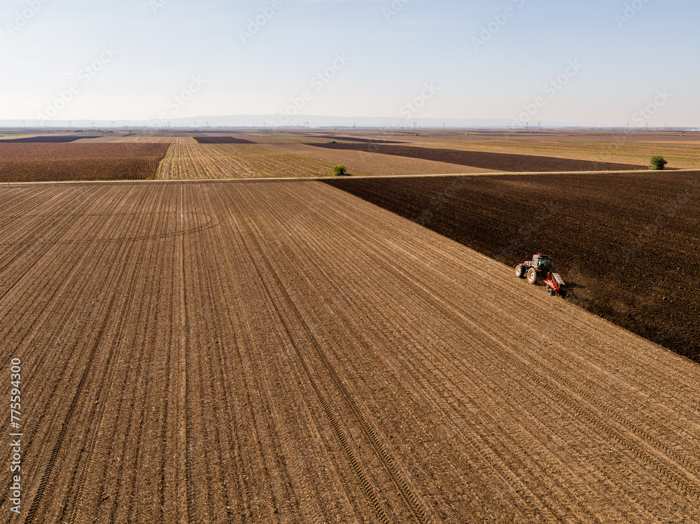 Tractor preparing the land for planting in vast agricultural fields, captured from above