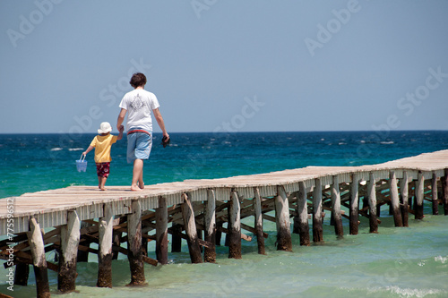 Alcudia, Playa de Muro, Muro beach, Majorca, Mallorca, Spain, Europe - young father and little son walking hand in hand on wooden planks pier at the seaside, Muro beach