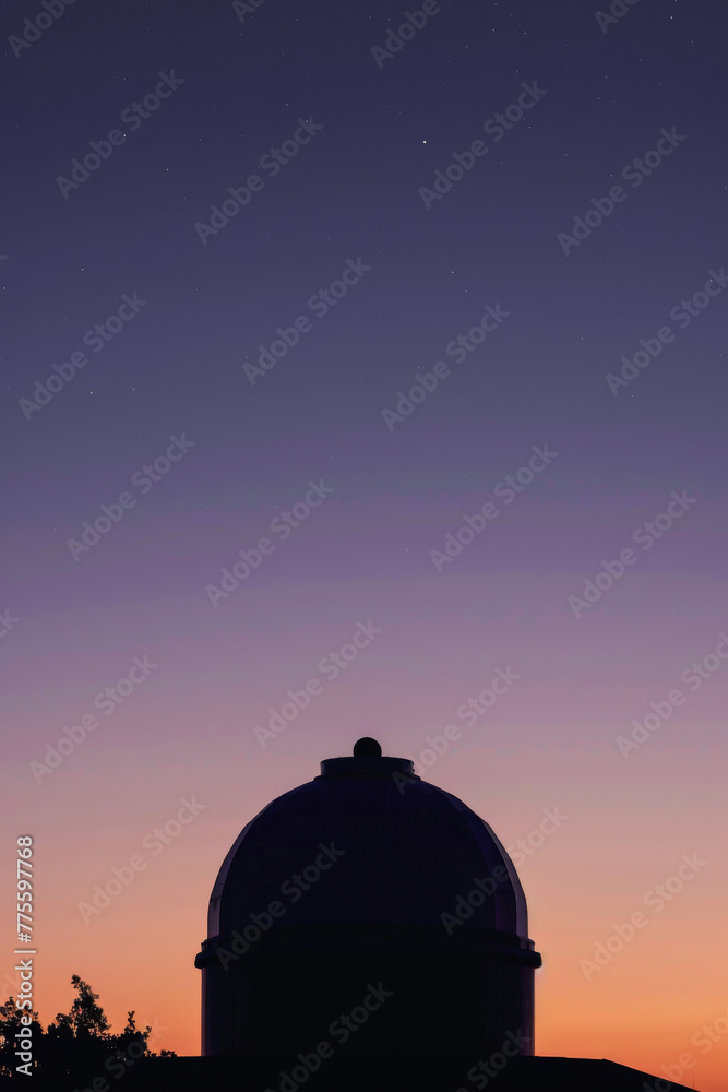 A large dome-shaped building is silhouetted against a purple sky