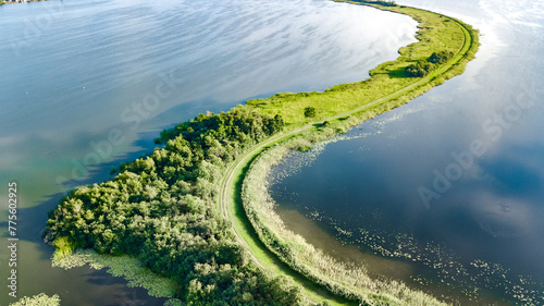 Aerial drone view of path on dam in polder water from above, landscape and nature of North Holland, Netherlands
