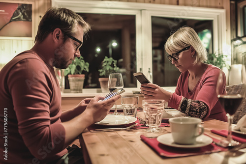 Couple using cell phones and ignoring each other during dinner at home