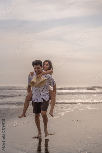 Couple in love having fun carrying each other on their backs on the beach