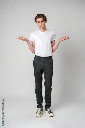 Canvas Print Young Man in White T-Shirt Displaying Uncertain Gesture Against Light Background