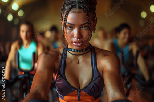 African American spinning class: slender woman enjoys herself during an exercise class, beaming with joy amidst a warm ambiance and serious charm. 