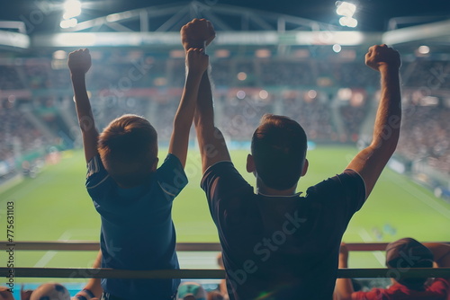 Dad and son cheering on a football match with raised hands photo