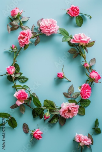 Pink roses and green leaves in a circle frame on a mint pastel floral background.
