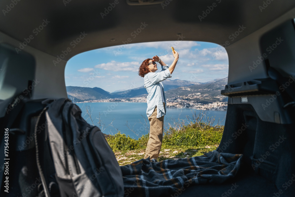 Young woman traveler looking for a mobile phone and internet signal while traveling by car at sea