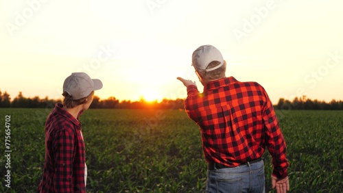 Man and woman agronomist colleagues discuss cultivation hitting hands at corn field closeup. Two farmer partners work as team consulting talking agriculture farming organic plant produce at sunset