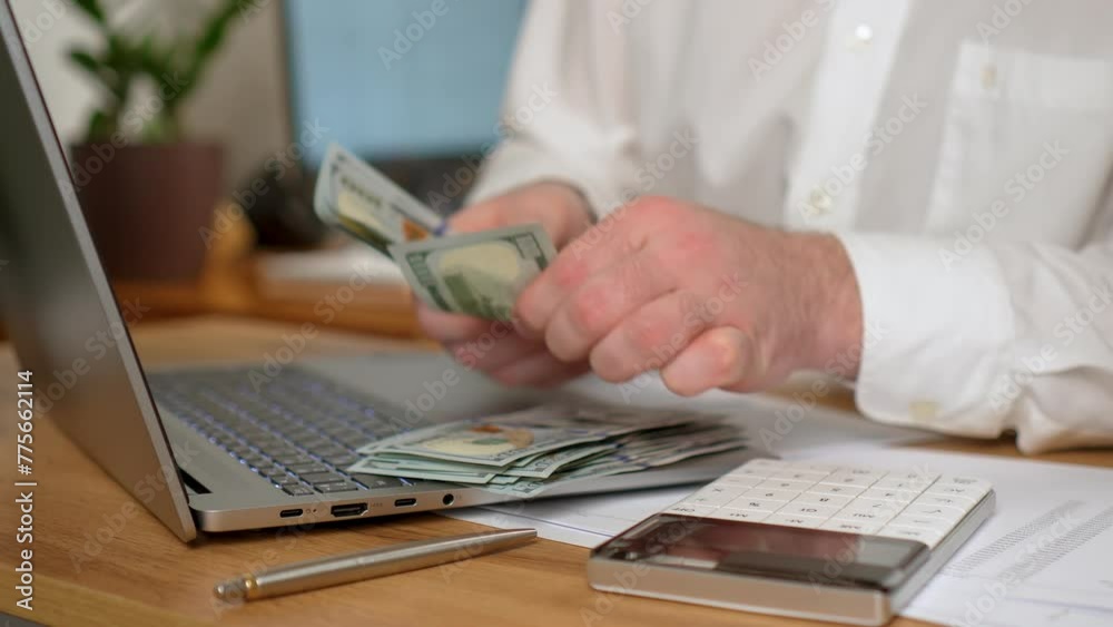 Man settling accounts tax calculation and counting money. dollars cash close up. Male Businessman working at home office with online trading market finance digital data