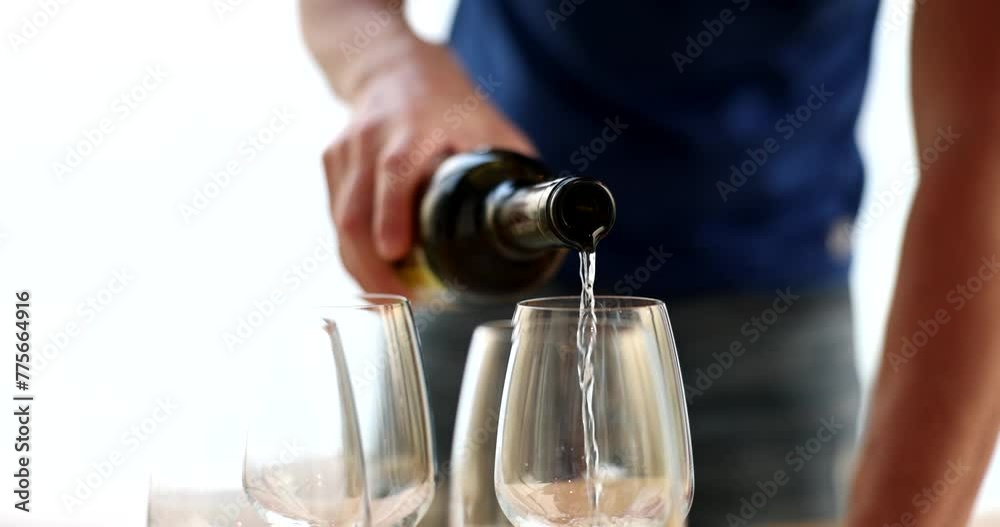 Closeup of hands of waiter or man pouring wine into glass indoors Closeup of hands of waiter or man pouring wine into glass indoors