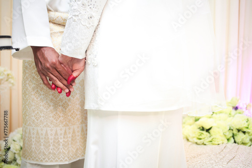 Young married couple holding hands, ceremony wedding. Malay wedding reception.