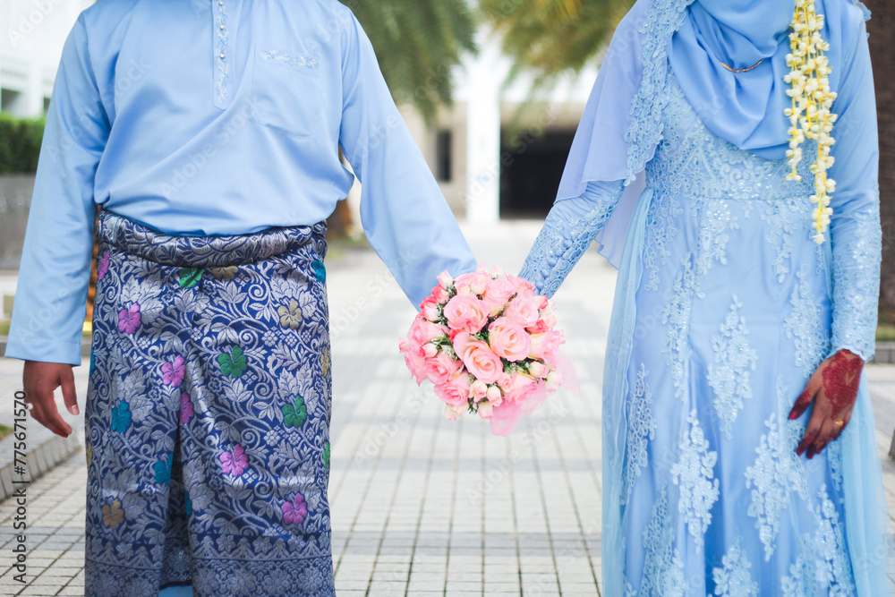 Obraz premium Malay wedding theme, holding hands newlyweds. Beautiful young adult couple.