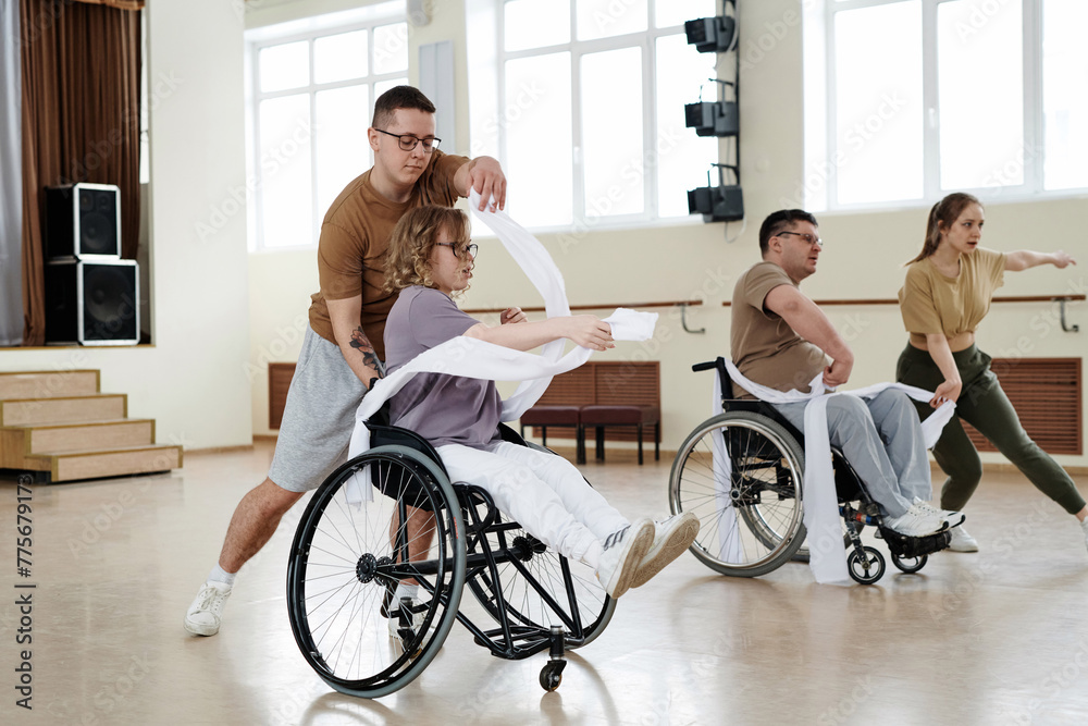 Group of four diverse men and women practicing dance with wheelchairs in studio, long shot Group of four diverse men and women practicing dance with wheelchairs in studio, long shot