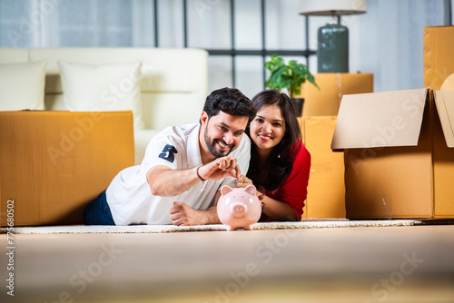 Indian young couple and saving concept with piggy bank and home moving with boxes