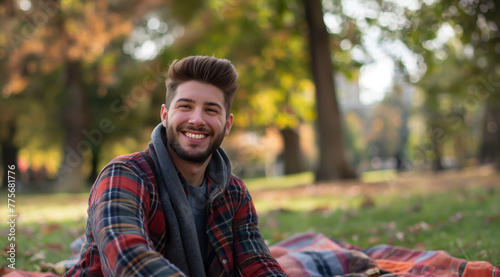 young handsome man or student sitting in the park on a picnic blanket in a good mood in nature © Steffen Kögler