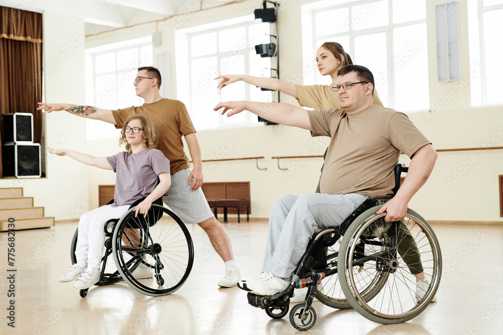 Group of four diverse active men and women practicing dance with wheelchairs in spacious studio, long shot Group of four diverse active men and women practicing dance with wheelchairs in spacious studio, long shot