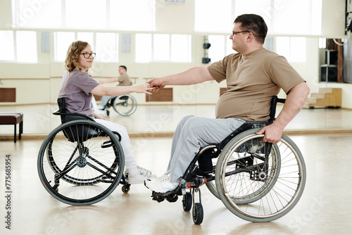 Long shot of Caucasian man and woman in wheelchairs practicing dance in spacious studio