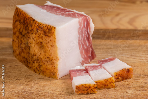 Slices and piece of salted pork fatback on cutting board photo