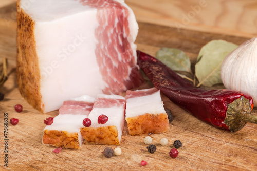 Partly sliced salted pork fatback among spices on cutting board