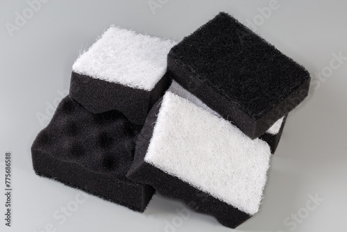 Black and white synthetic cleaning sponges on a gray background