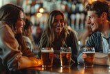 Three happy friends talking and laughing in a bar while drinking beer.