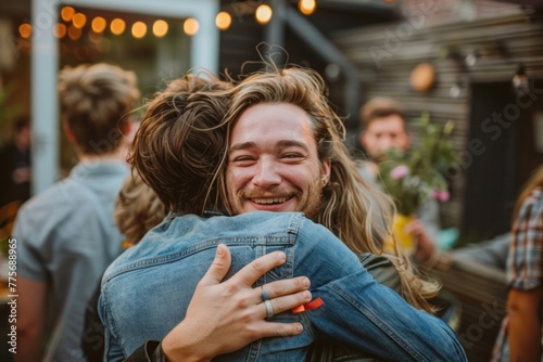 Two cheerful young men hugging each other outside in the garden during a party.