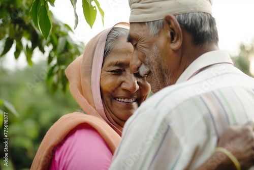 Portrait of senior old smiling Indian couple in love hugging standing in the garden